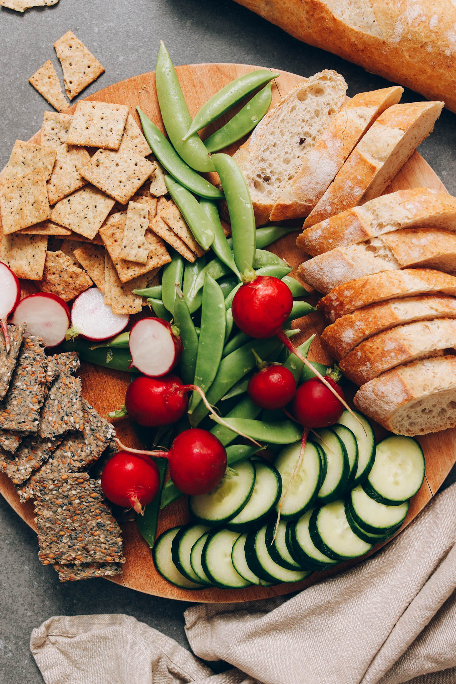 Round platter with bread, cucumbers, radishes, and crackers 