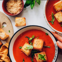 Bowl of vegan tomato soup with croutons and basil on top
