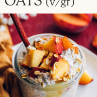 Jar of vegan and gluten-free peaches and cream overnight oats with fresh peaches on top and a spoon in it