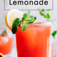 Glass of easy homemade strawberry lemonade with fresh lemon and mint on the side