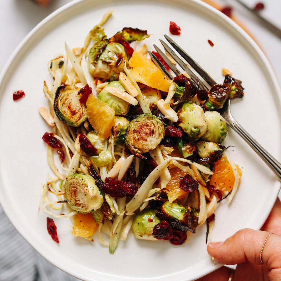 Holding a plate of roasted brussel sprout and fennel salad