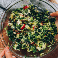 Tossing a shaved brussel sprout kale salad with dressing