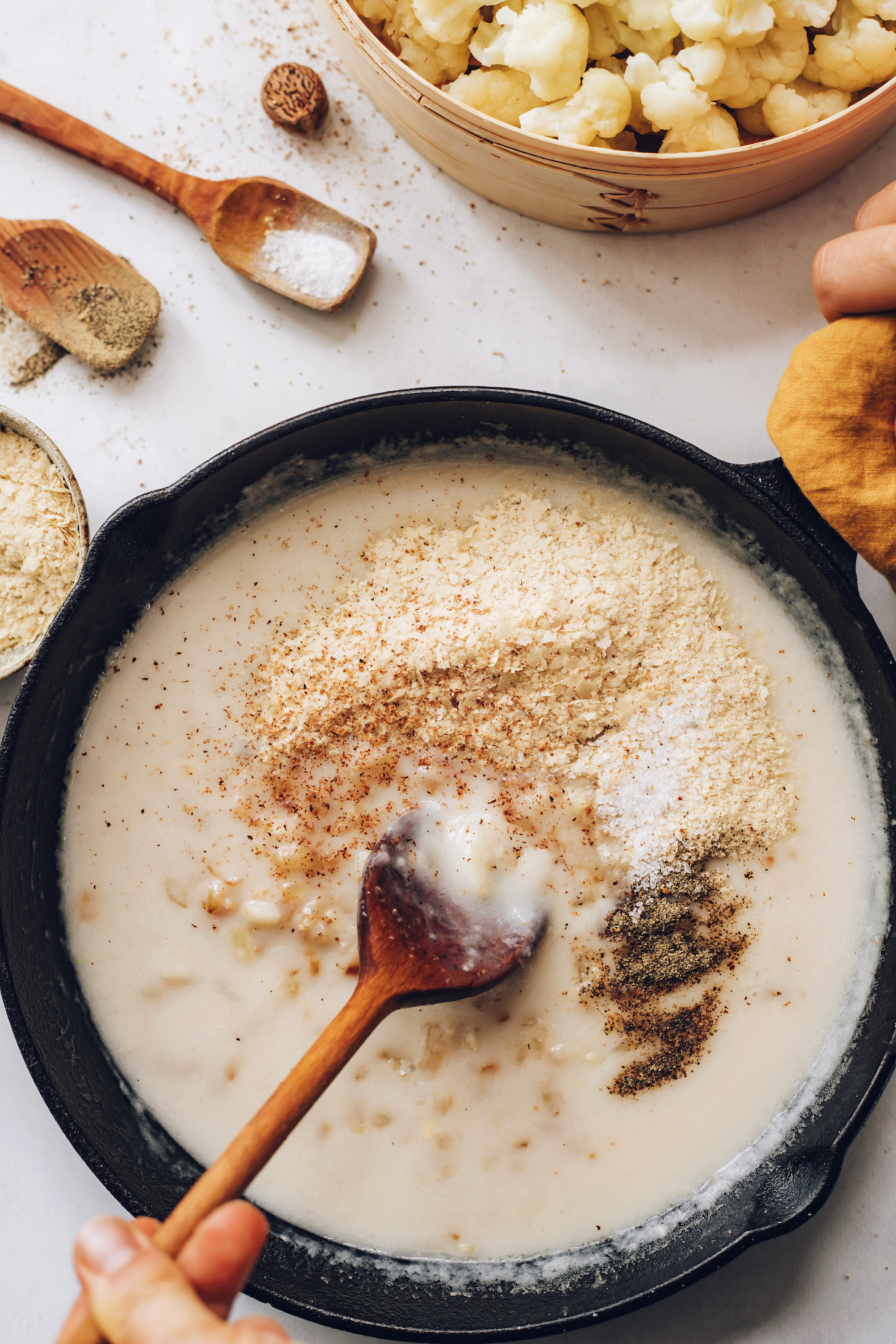 Kremalı vegan beyaz sos üzerine serpilmiş besleyici maya, hindistan cevizi, tuz ve karabiber