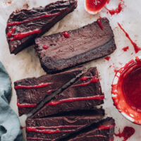 Slices of vegan gluten-free chocolate cheesecake with raspberry sauce