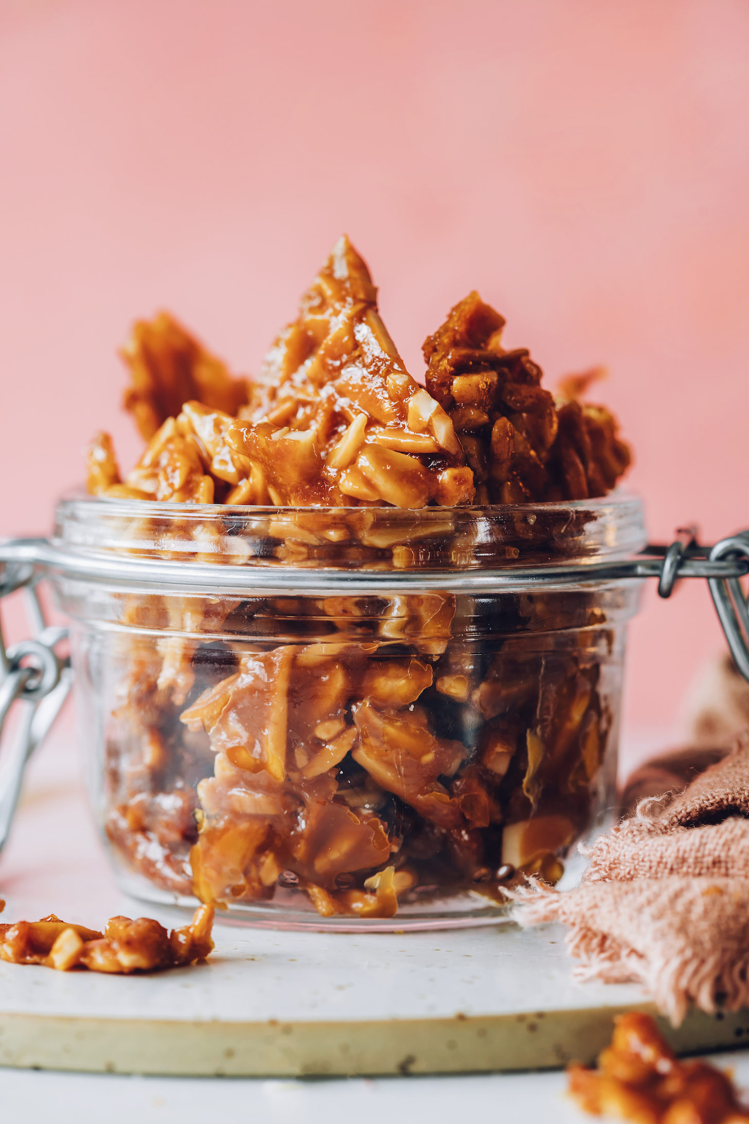 Overflowing jar of crunchy almond brittle peices
