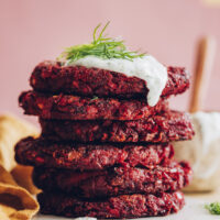 Stack of beet fritters topped with vegan yogurt sauce