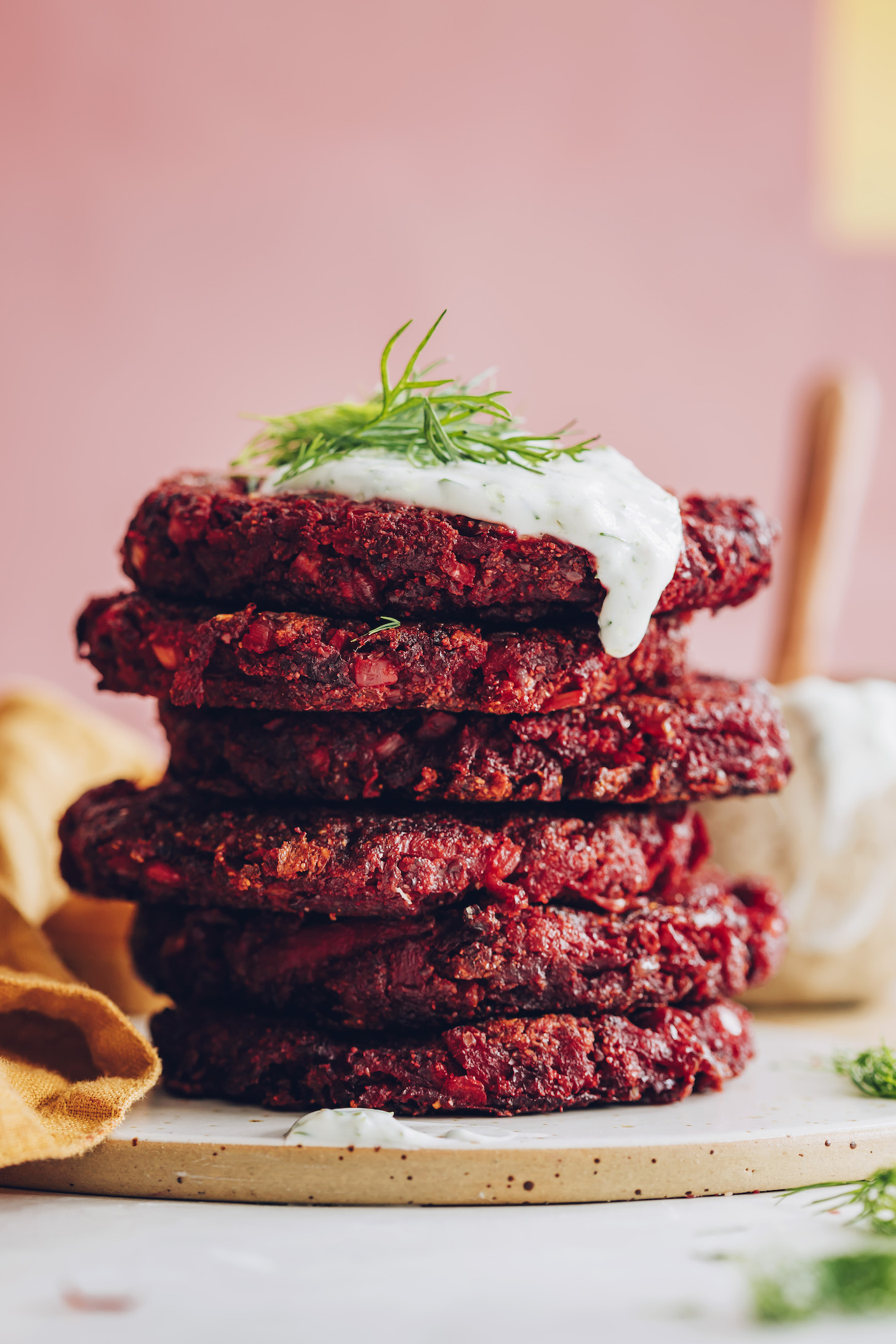 Stack of beet fritters topped with dill yogurt sauce and fresh dill