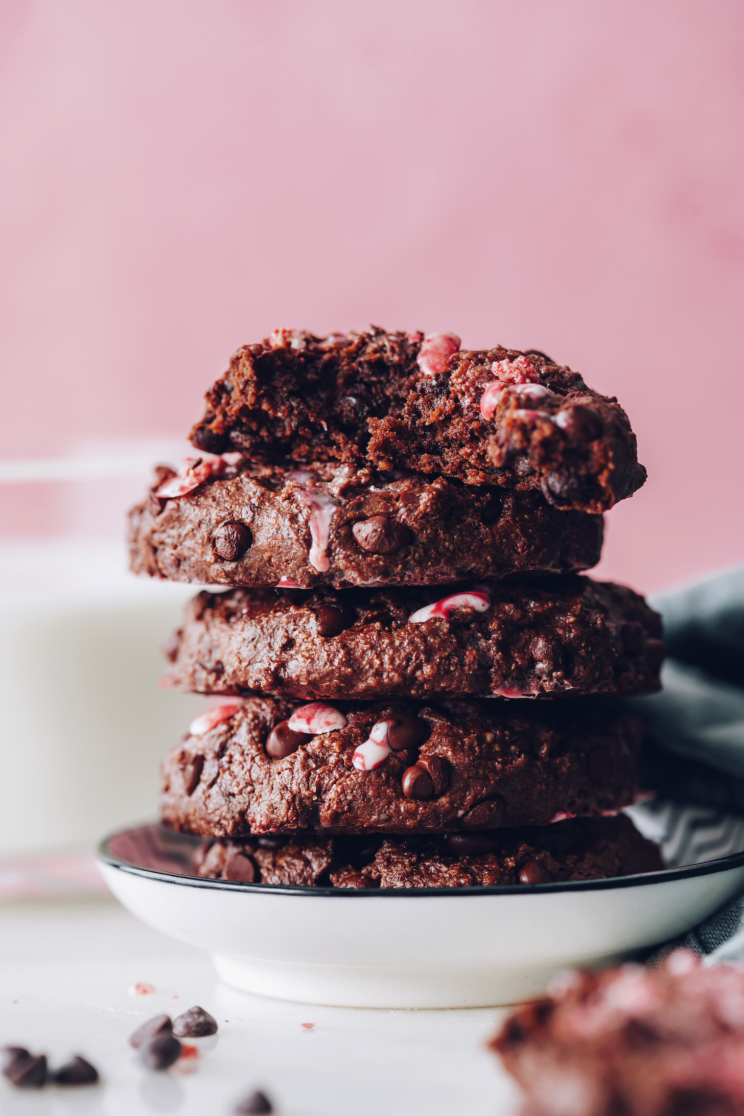 Showing the fudgy inside texture of a chocolate peppermint cookie on a stack of more cookies