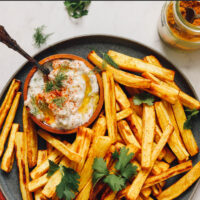 Plate of curry roasted parsnip fries with a dish of zesty dill yogurt sauce on the side
