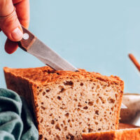 Knife slicing a loaf of vegan and gluten-free no-knead sandwich bread