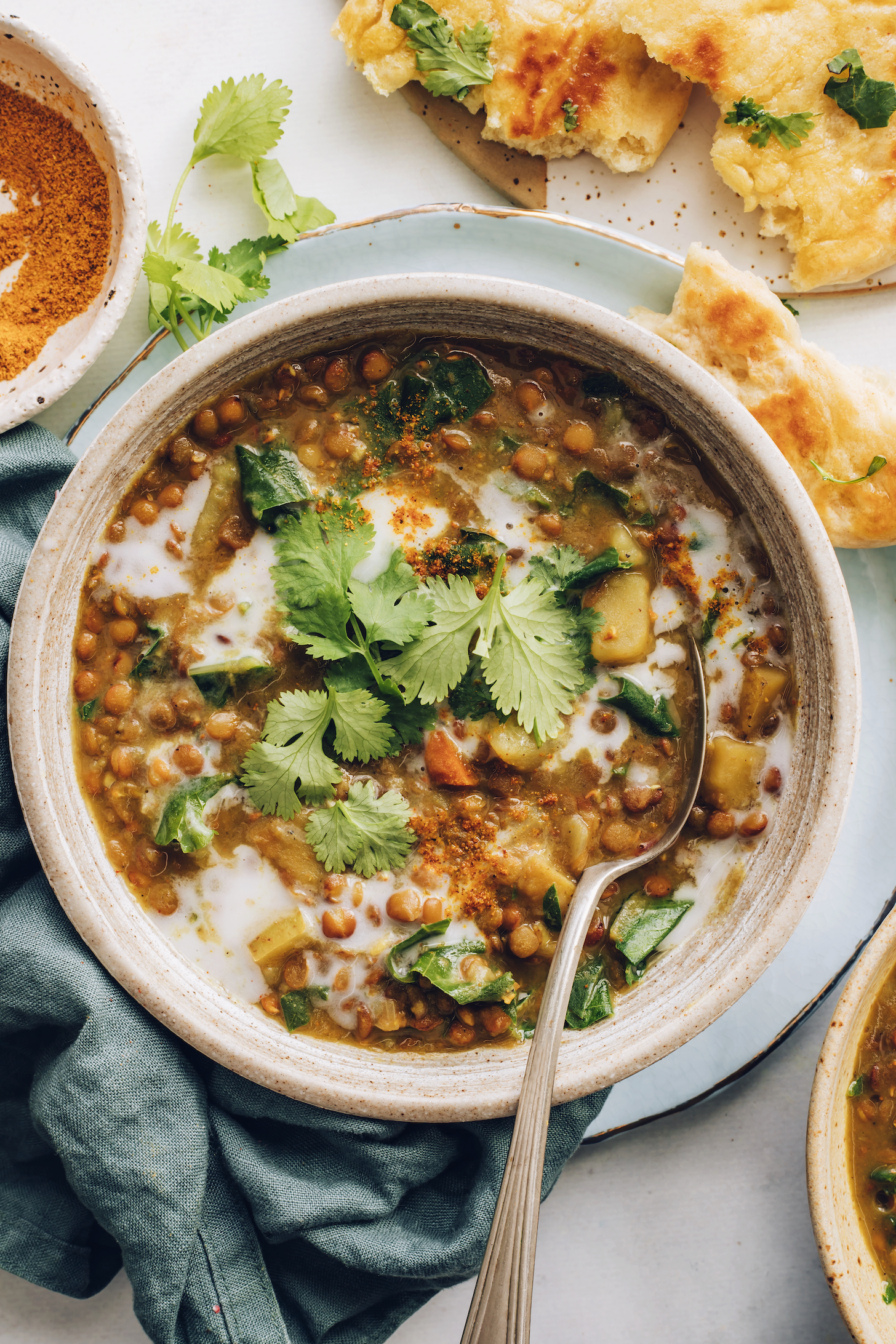 Vegan naan next to a bowl of Instant Pot lentil soup topped with cilantro and curry powder