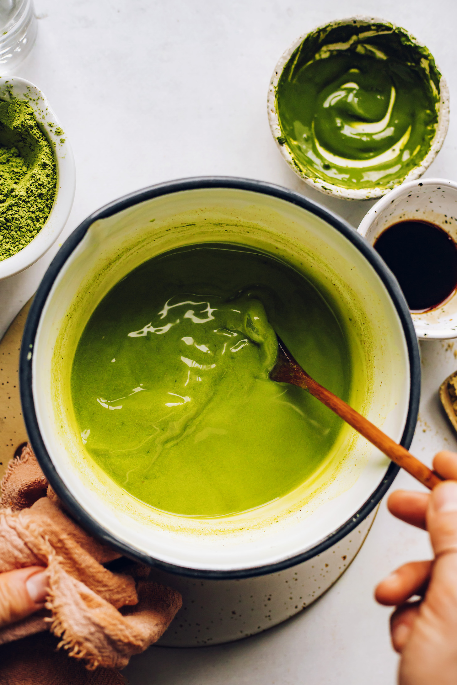 Stirring matcha, coconut milk, spices, and sweetener in a white saucepan