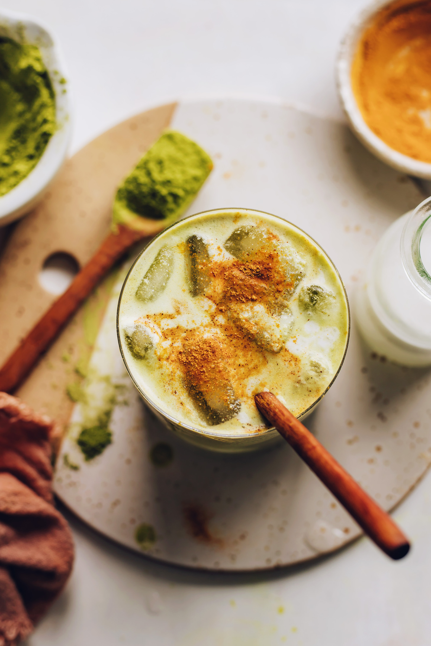 Spices sprinkled on a glass of iced golden matcha latte