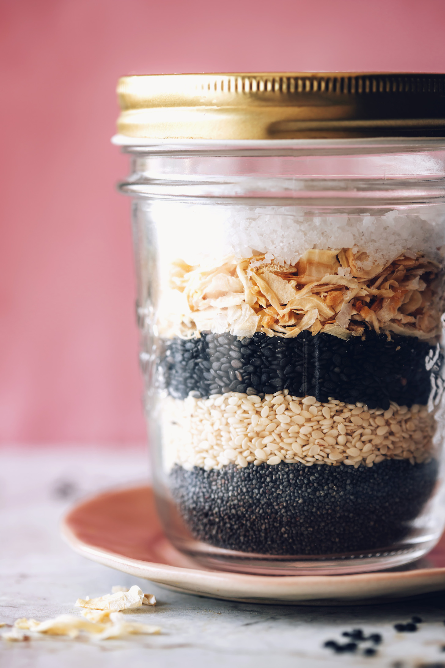 Jar with layers of poppy seeds, white sesame seeds, black sesame seeds, minced onion and garlic, and salt