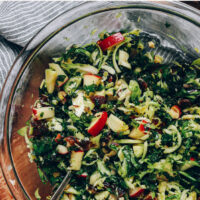Bowl of vegan and gluten-free shaved brussels sprout salad with apples and dates