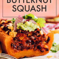 Plate of vegan and gluten-free enchilada-stuffed butternut squash with guacamole on top