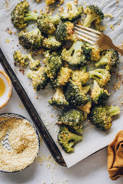 Baking sheet of perfectly roasted broccoli with vegan parmesan