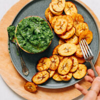 Plate of roasted plantains with a bowl of magic green sauce