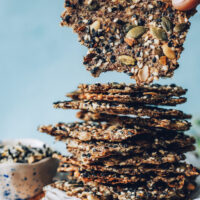Holding a seed cracker beside a stack of more crackers