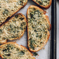 Slices of vegan garlic bread on a baking sheet
