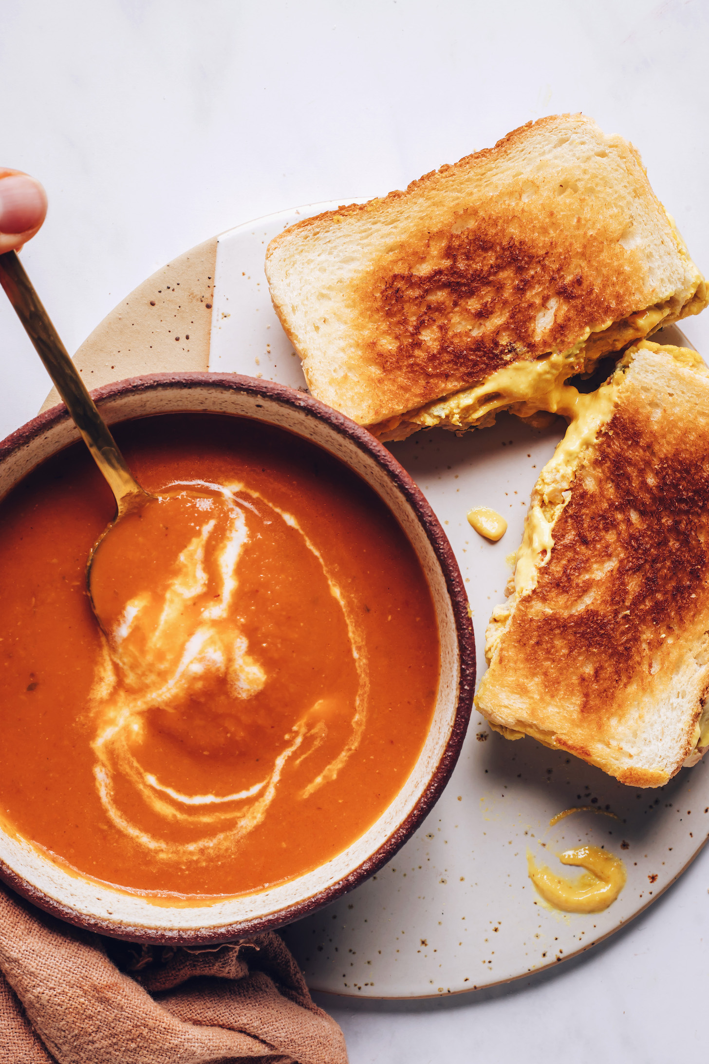 Vegan chickpea tuna melt next to a bowl of spicy tomato soup