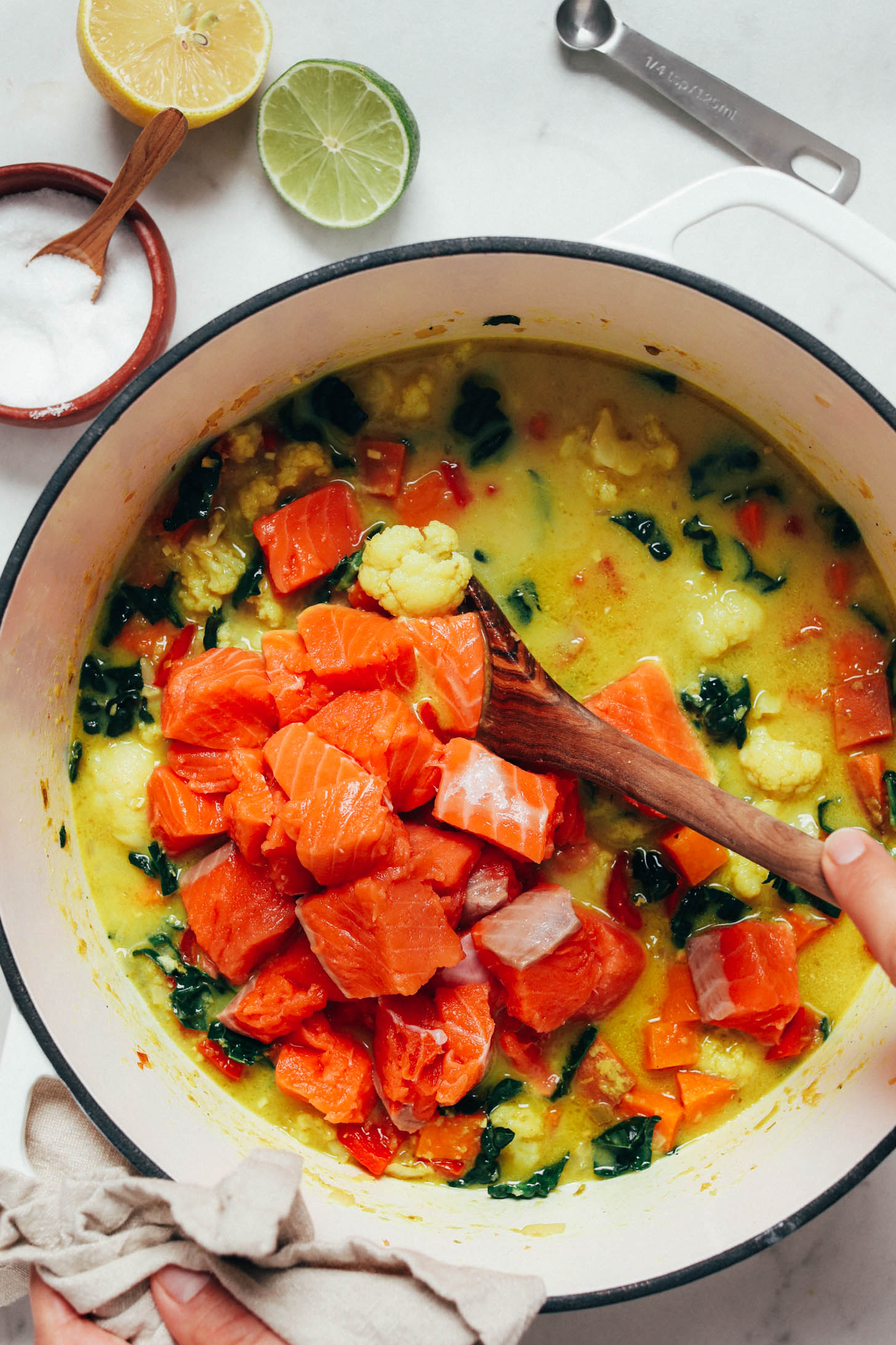 Stirring cubed salmon into green curry