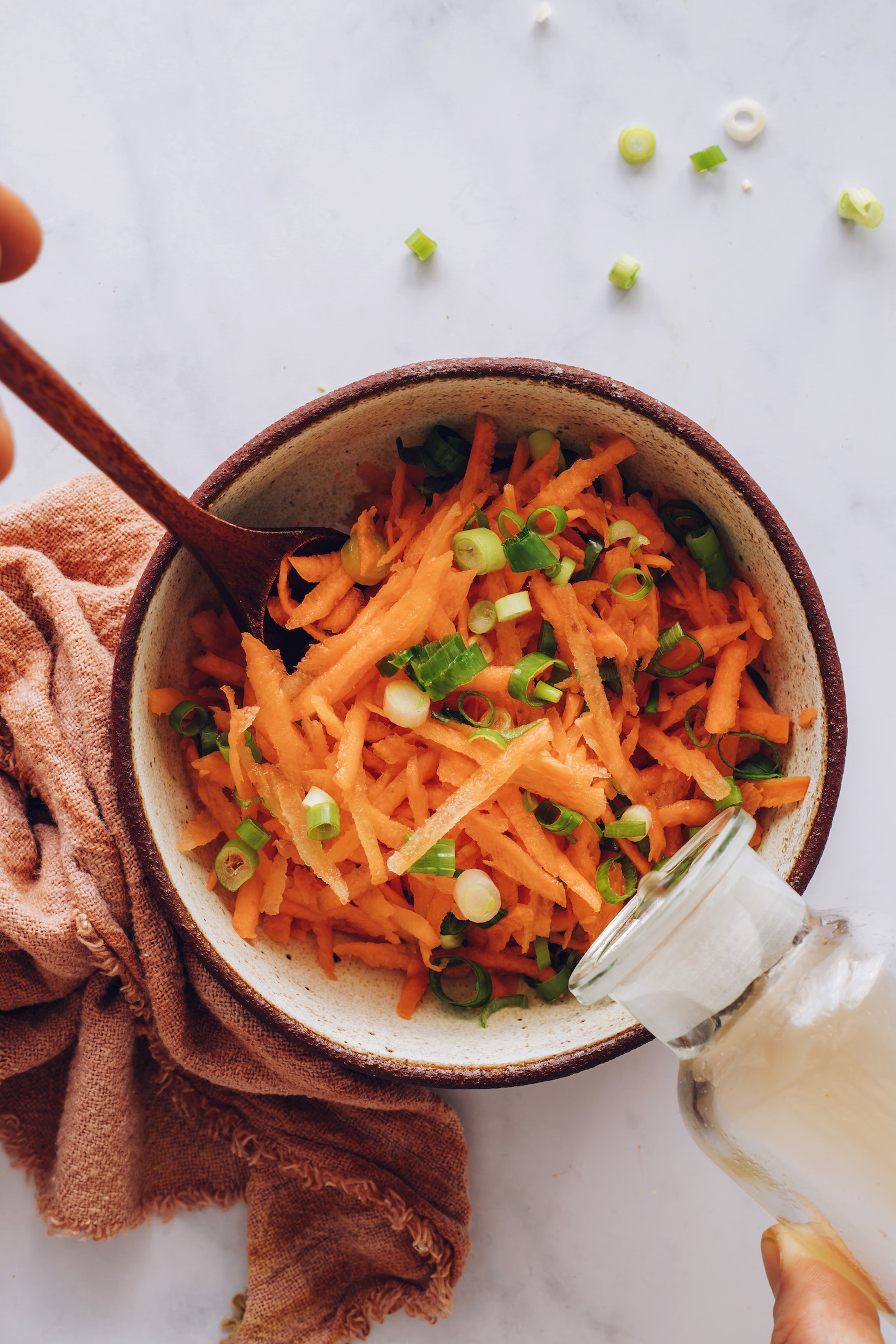 Ajouter du vinaigre de riz aux carottes râpées et aux oignons verts