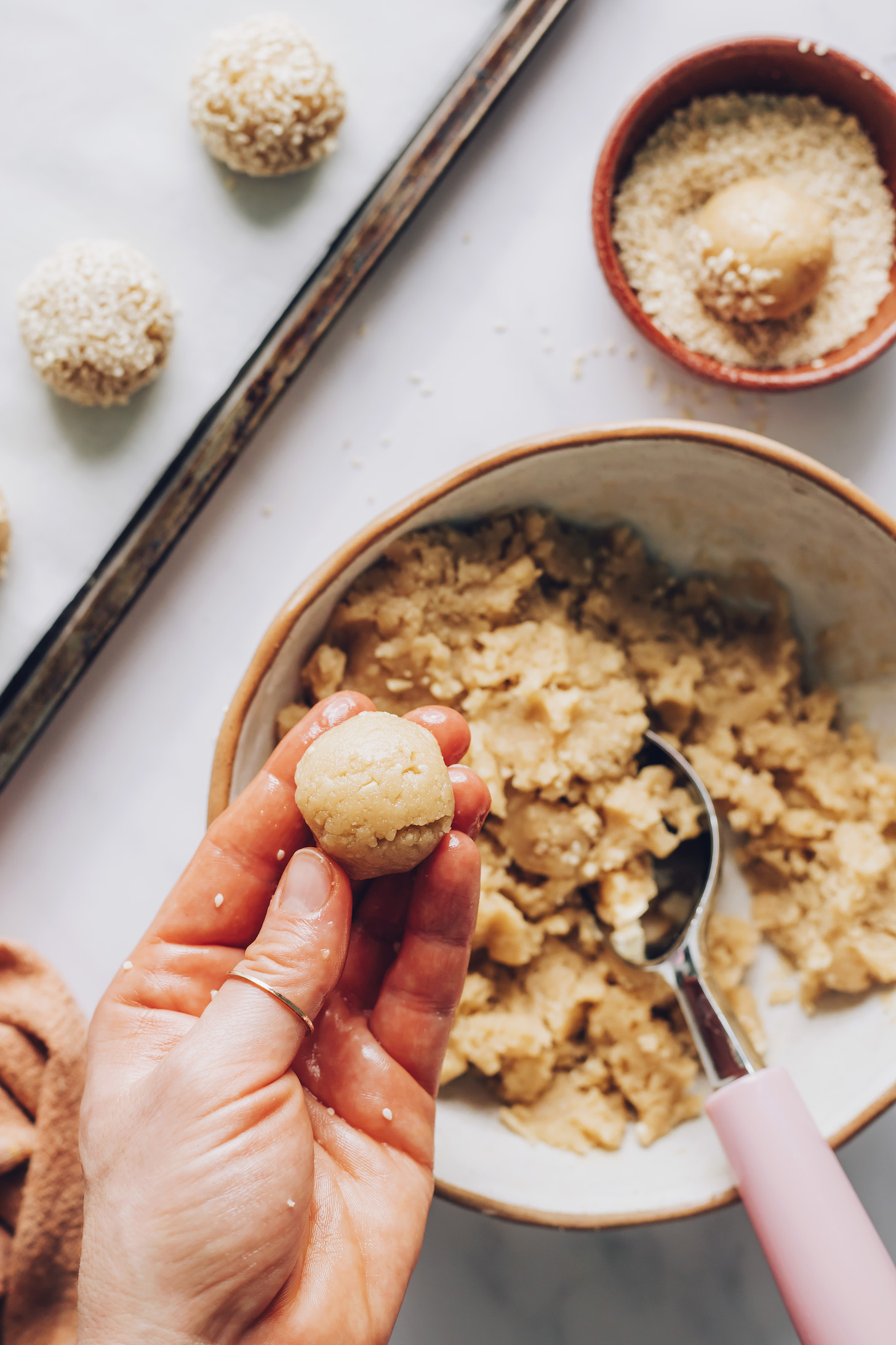 Holding a ball of cookie dough over a mixing bowl