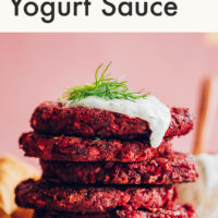 Stack of vegan and gluten-free beet fritters with dill yogurt sauce and fresh dill on top