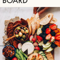 Hands grabbing snacks off of a vegan "charcuterie" board