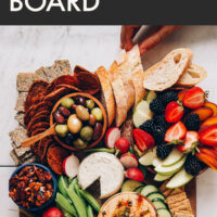 Hands grabbing snacks off of a vegan "charcuterie" board