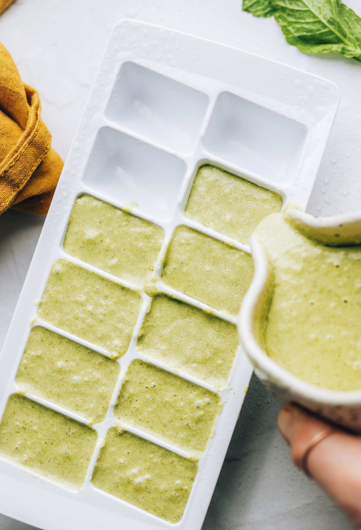 Blended mint chocolate soft serve ingredients being poured into an ice cube tray