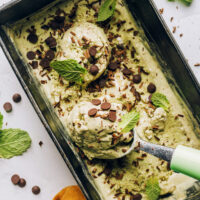 Ice cream scoop in a pan of vegan mint chocolate chip ice cream