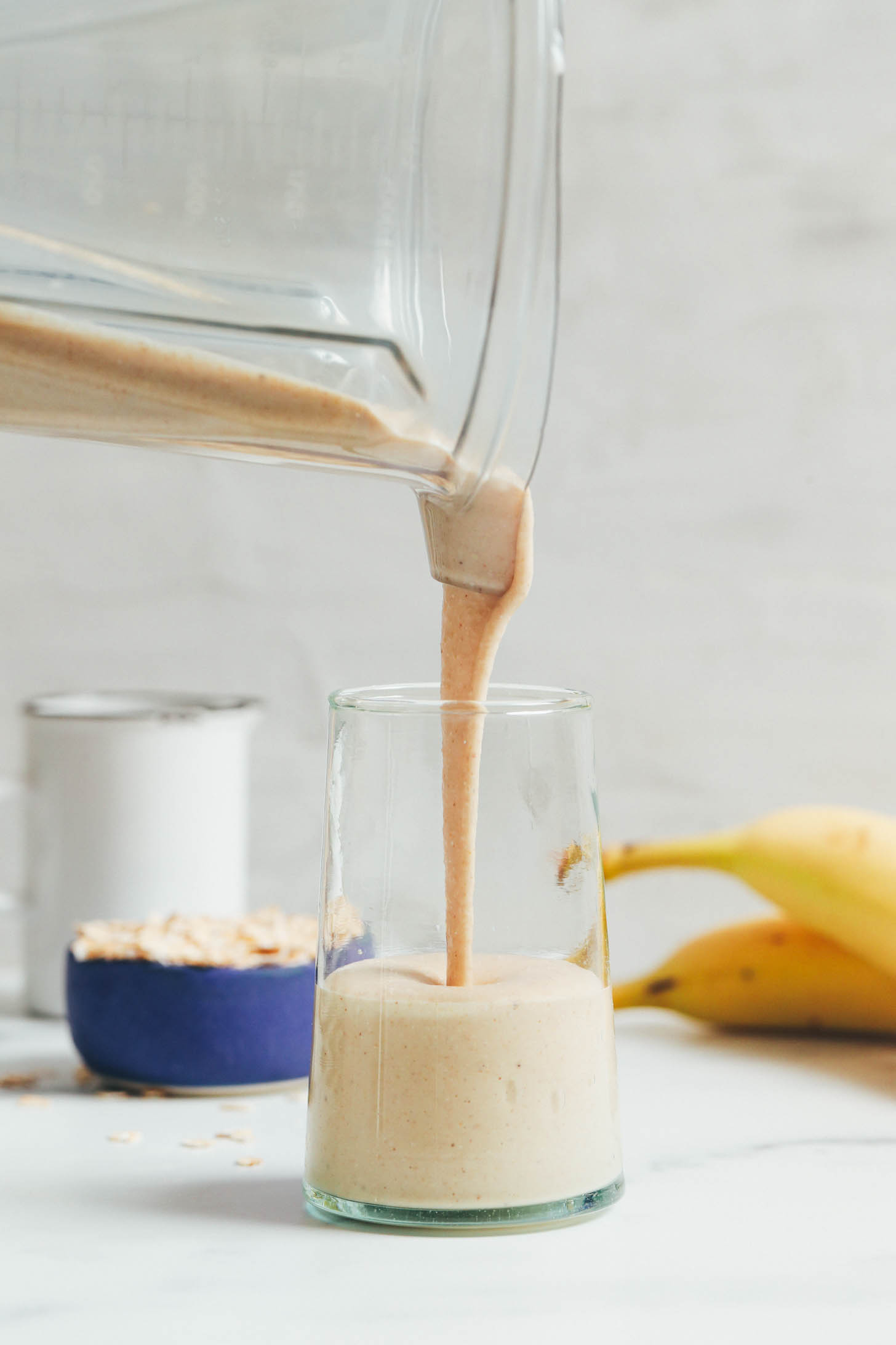 Pouring a peanut butter banana smoothie from a blender into a glass