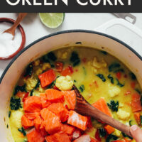 Stirring cubed salmon into a pot of green curry