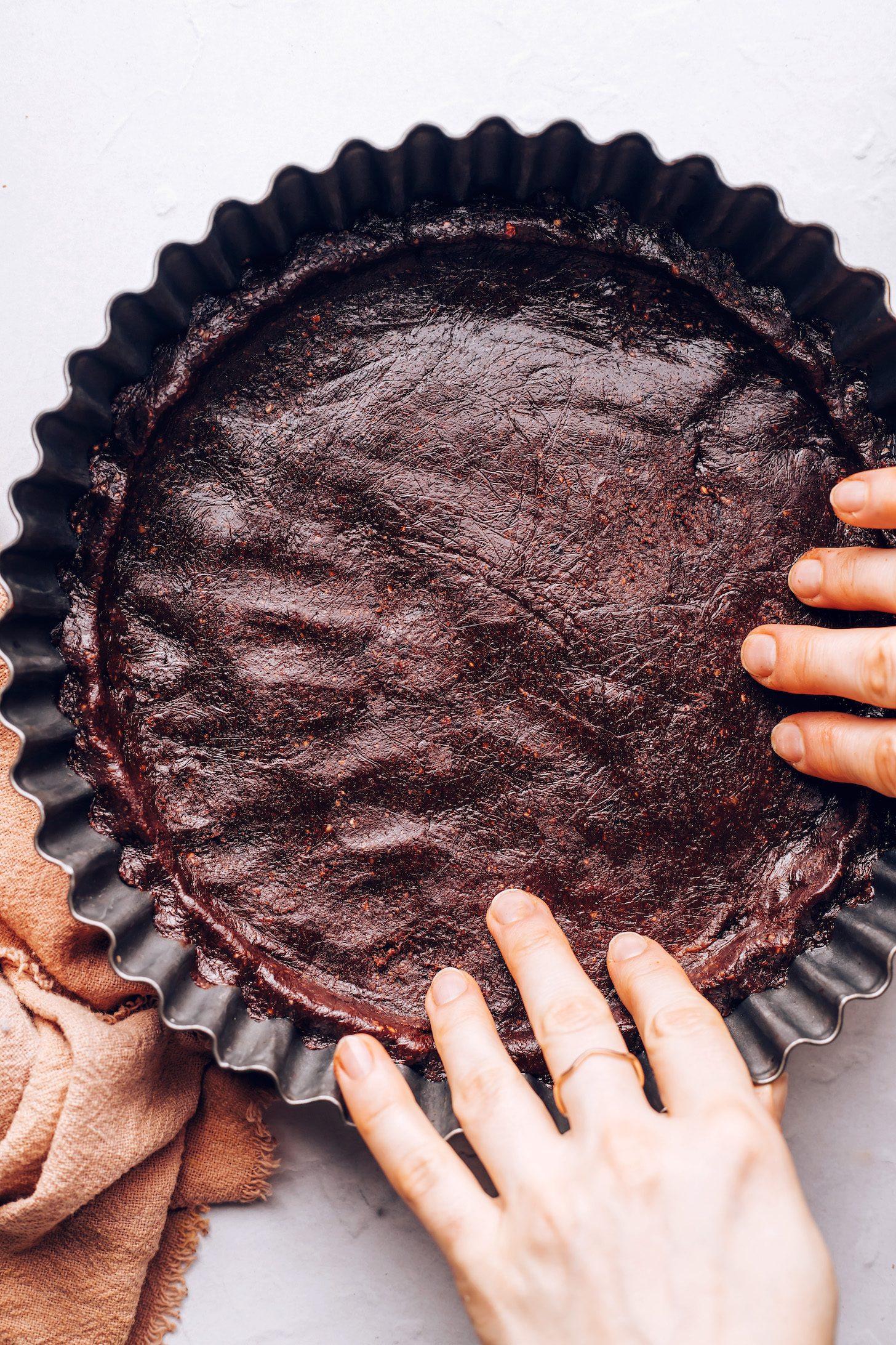 Pressing a chocolate pecan crust into  a tart pan
