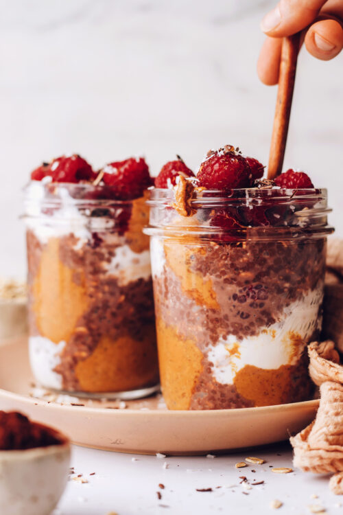 Two jars of chocolate overnight oats with fresh raspberries