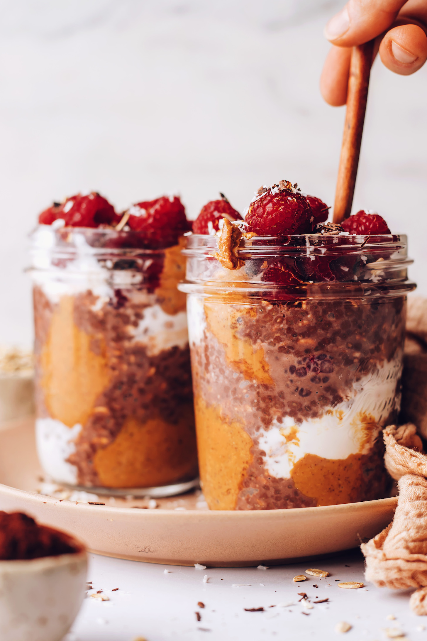 Holding a spoon in a jar of vegan chocolate overnight oats