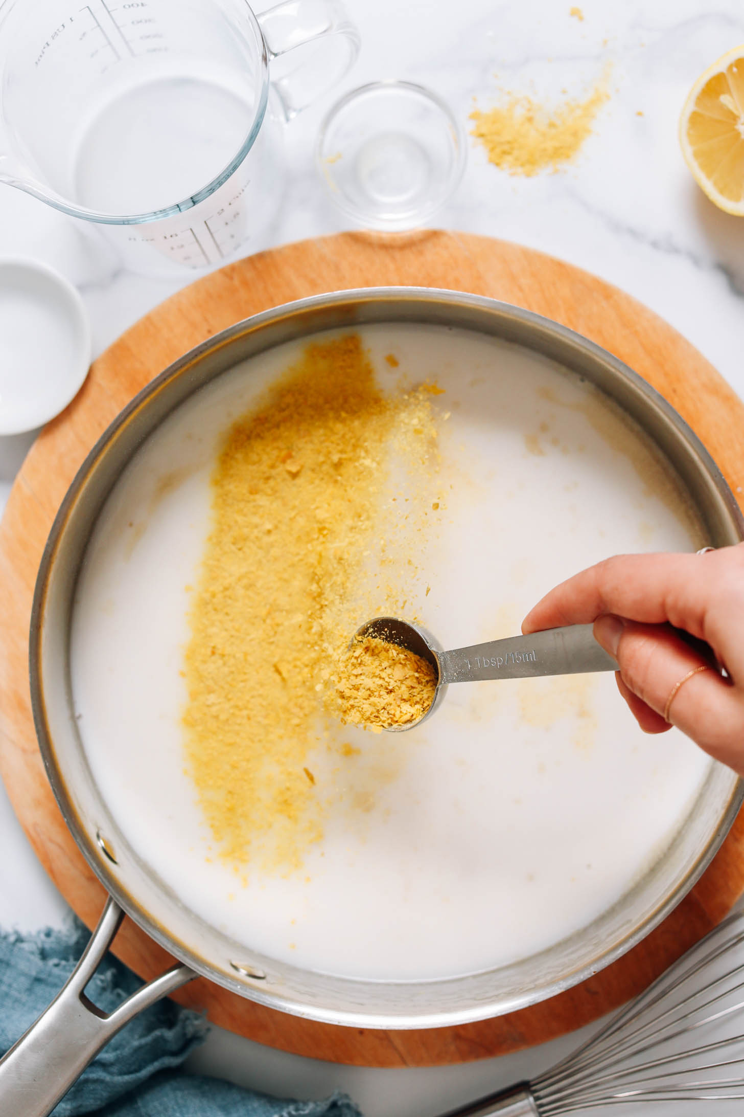Sprinkling nutritional yeast into a large skillet