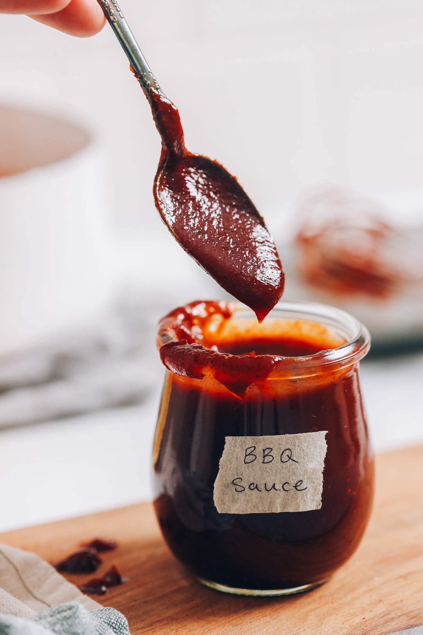 Holding a spoonful of homemade BBQ sauce over a jar with more sauce