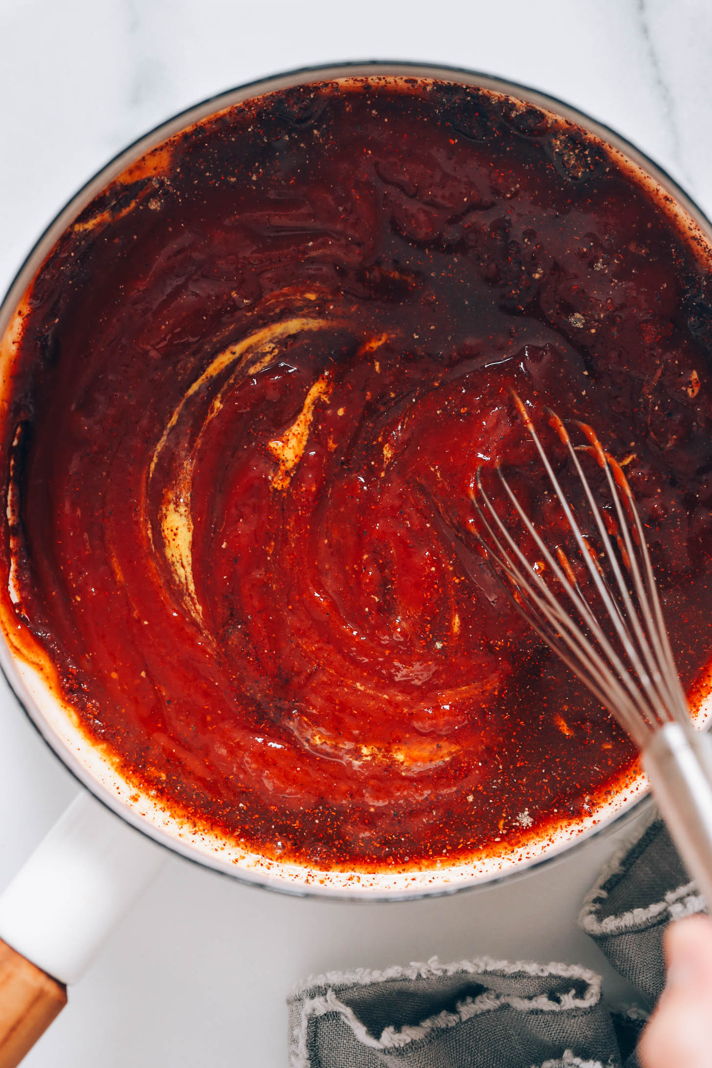 Using a whisk to combine the ketchup, mustard, spices, and other ingredients