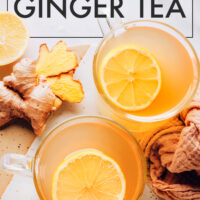 Mugs of fresh ginger tea with lemon slices on top