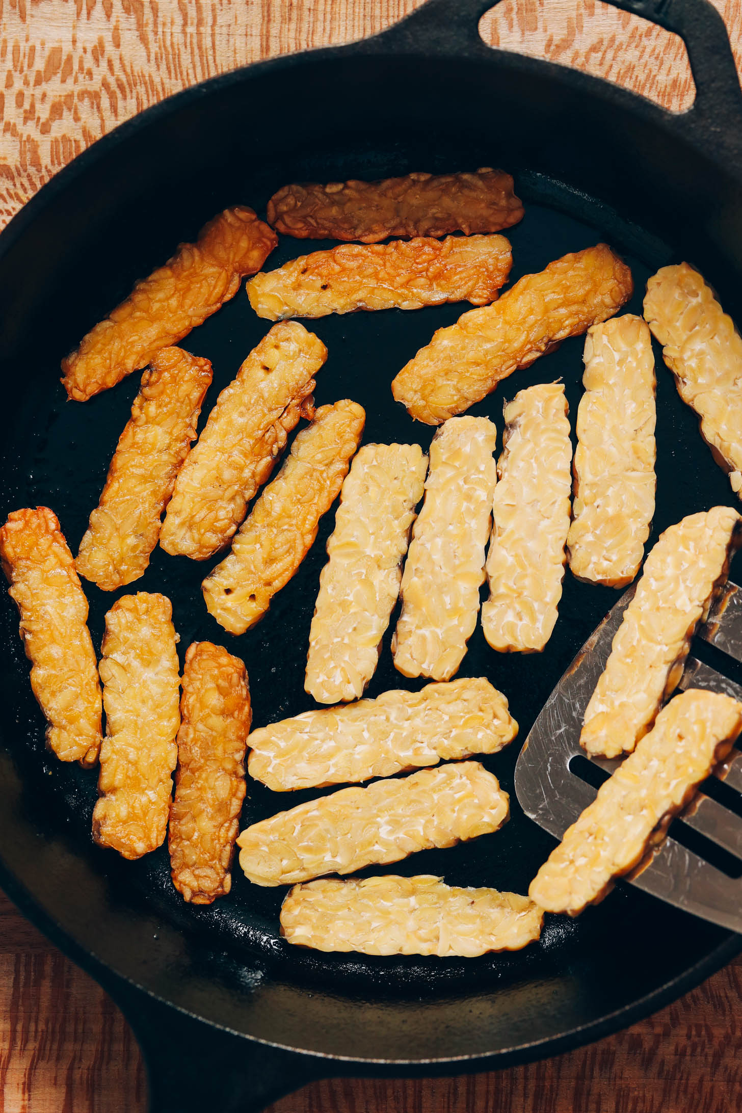 Cooking tempeh strips in a cast iron skillet
