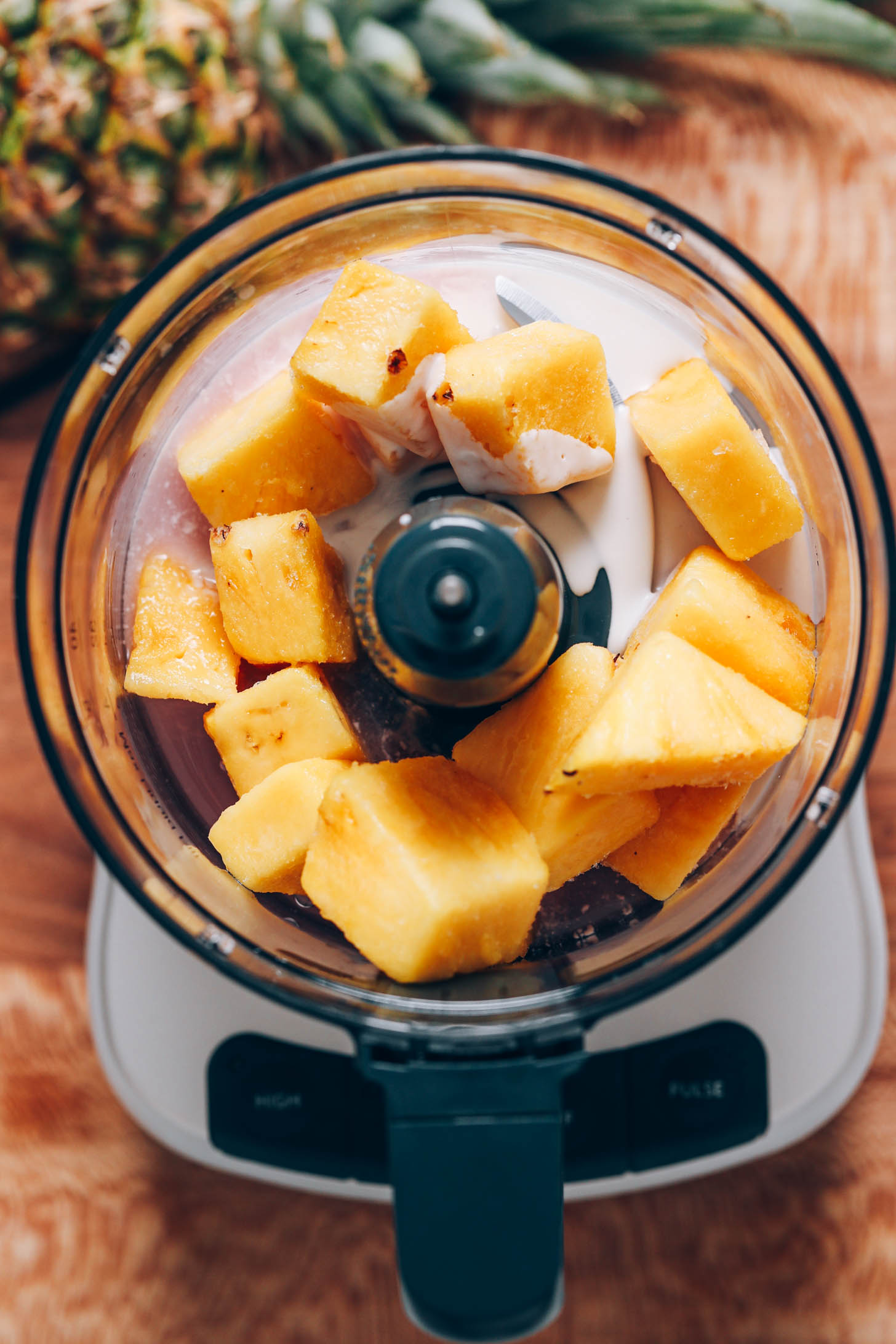 Bir mutfak robotunda ananas parçaları, hindistancevizi kreması ve hindistancevizi suyu