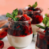 Jars of vegan panna cotta topped with a mixed berry compote