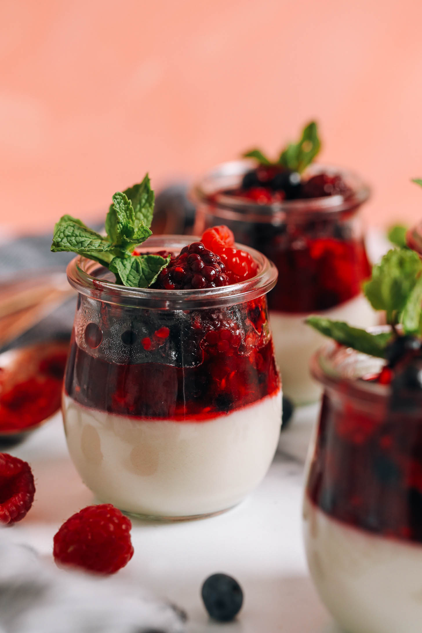Fresh mint leaves in jars of vegan panna cotta with mixed berries