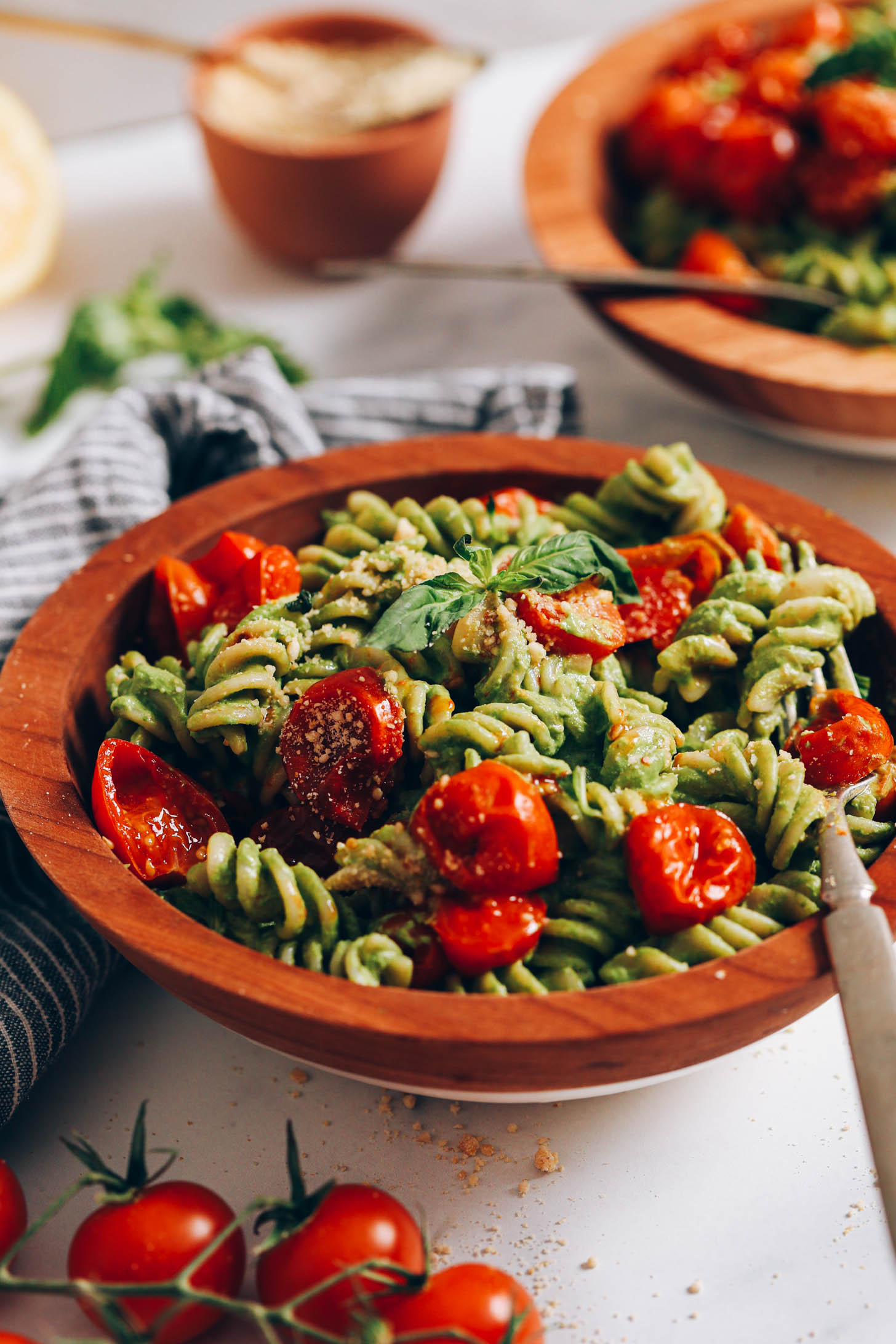 Two bowls of vegan pesto pasta with roasted cherry tomatoes