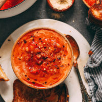 Vegan grilled cheese sandwich next to a bowl of tomato white bean soup