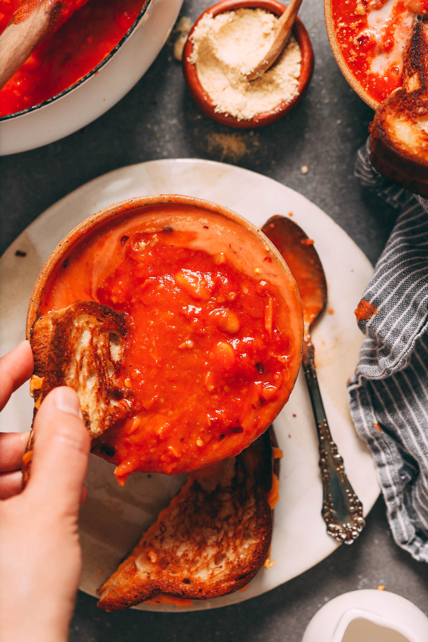 Izgara peynirli sandviçi bir kase domates ve beyaz fasulye çorbasına batırmak