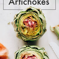 Plate of freshly cooked artichokes with vegan dipping sauces on the side